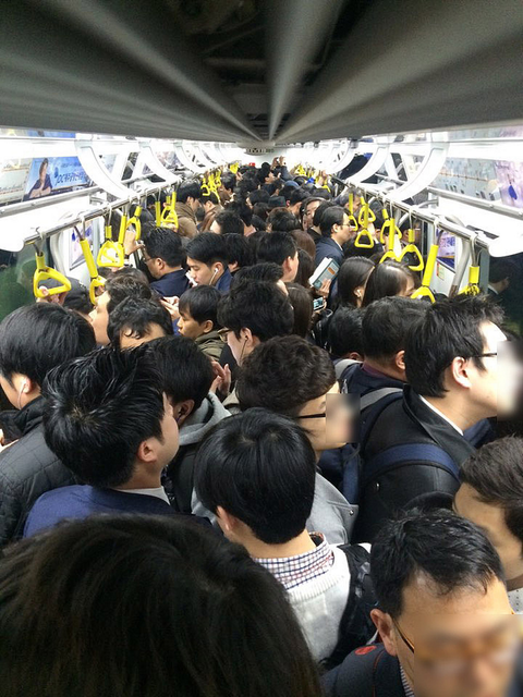 An extremely crowded train carriage packed with passengers.