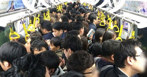 An extremely crowded train carriage packed with passengers.