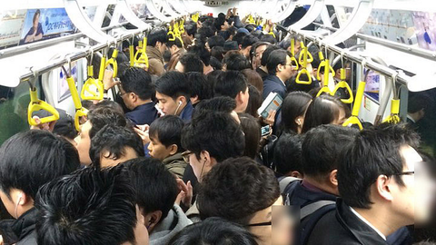 An extremely crowded train carriage packed with passengers.