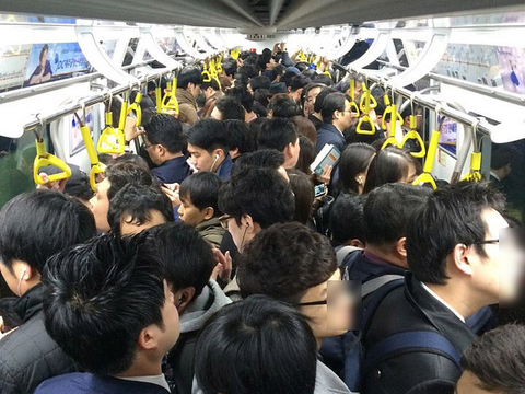 An extremely crowded train carriage packed with passengers.