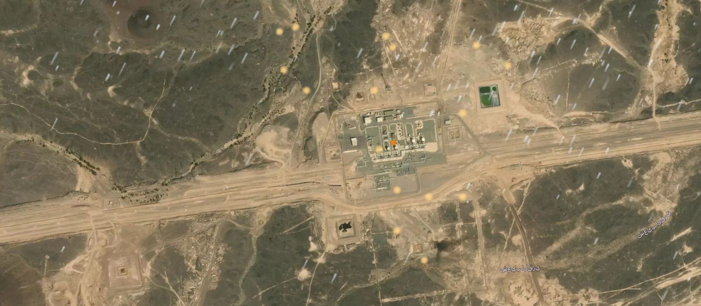 Satellite view of a fenced oil pumping station on Saudi Arabia's East-West pipeline near Al Mesba'ah, desert on both sides, the pipeline corridor running left to right
