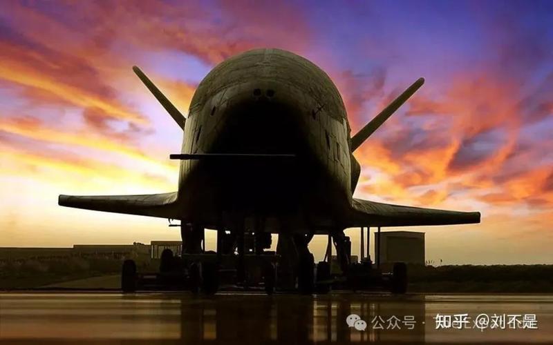 The X-37B spaceplane silhouetted on a runway against an orange and purple sunset