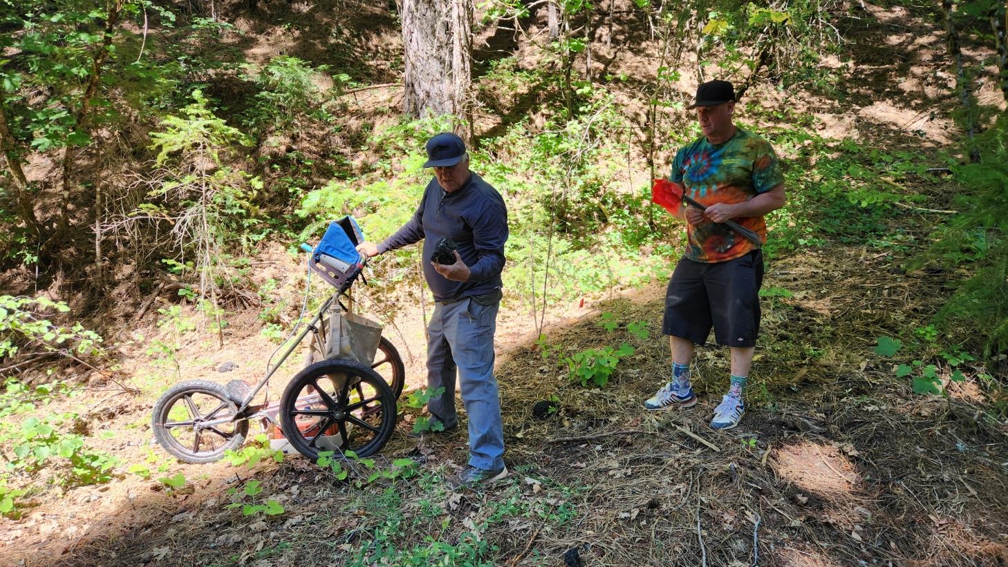 (Left) Tom Nicholson surveys the Pauper’s Graveyard area with ground-penetrating radar, then Mike Karsikis (right) uses flags to mark the discovered graves.