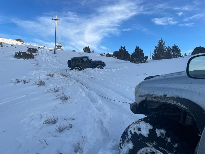 A 775 Offroad & Recovery vehicle winches a stuck Jeep out of the snow
