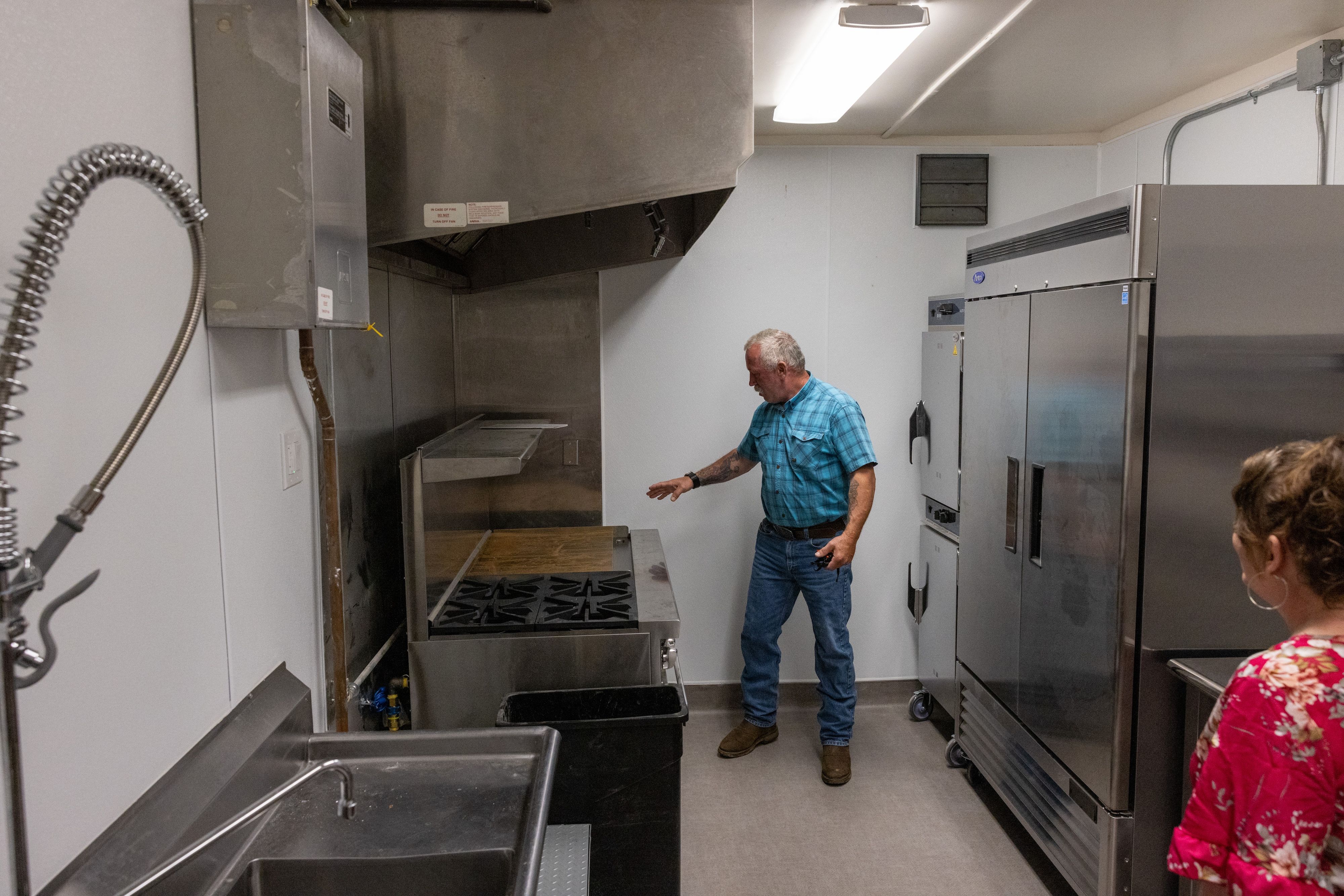 Billy Epps shows off the newly installed kitchen, which includes a commercial  stove and hood, refrigerator, warmer, sink, and storage space.