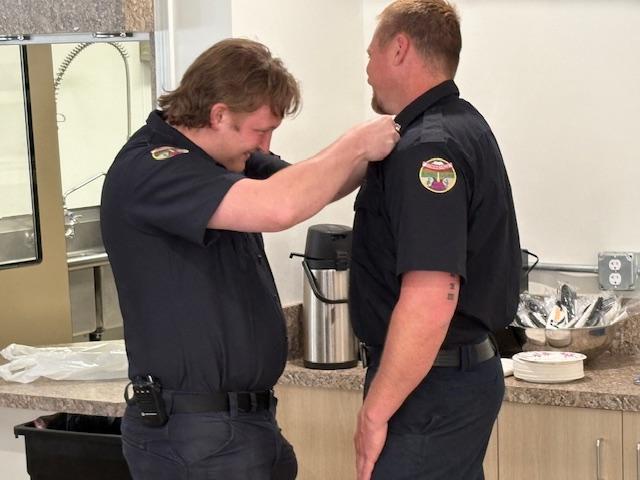 Tegan Harrington pins his EMS badge on Cory Schiemann.