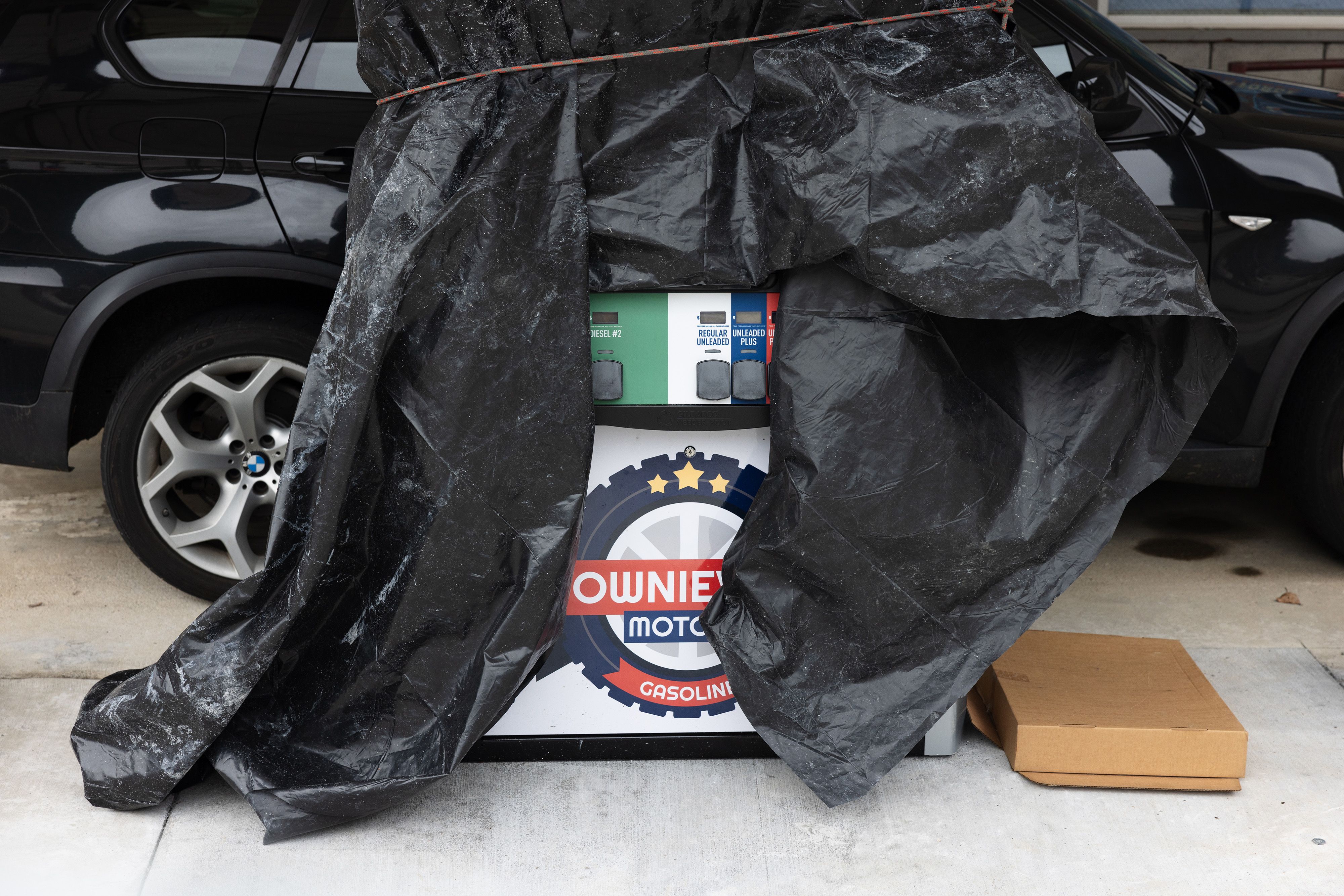 Branding and fuel options peek out from a tarp covering one of the newly installed pumps