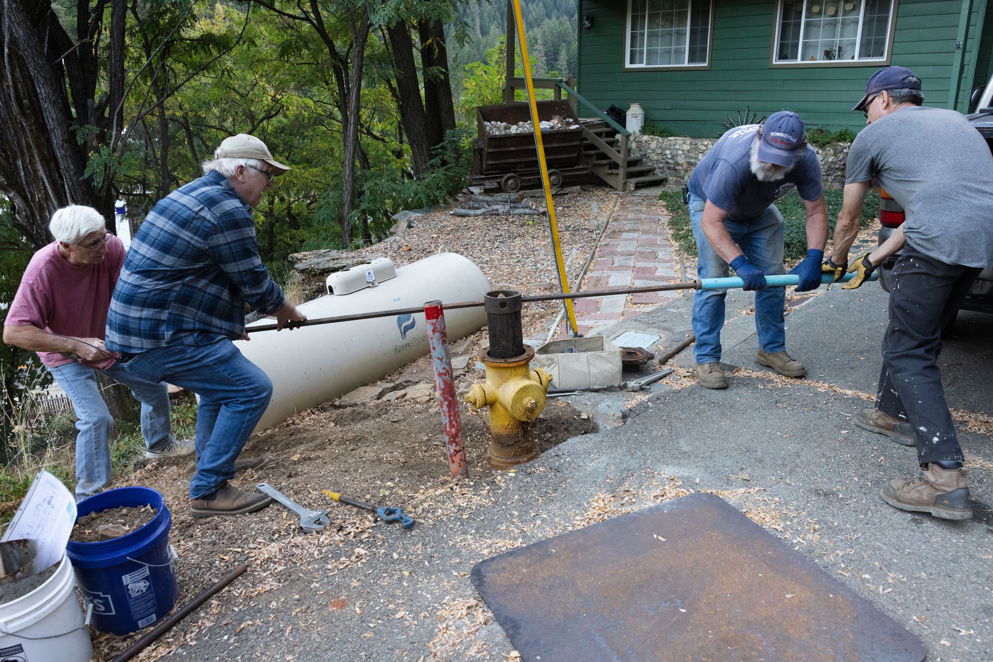 (Left to right) Paul Douville, Robert Hall, Dan McNamara, and Keith Loving work to loosen a nut at the base of the fire hydrant