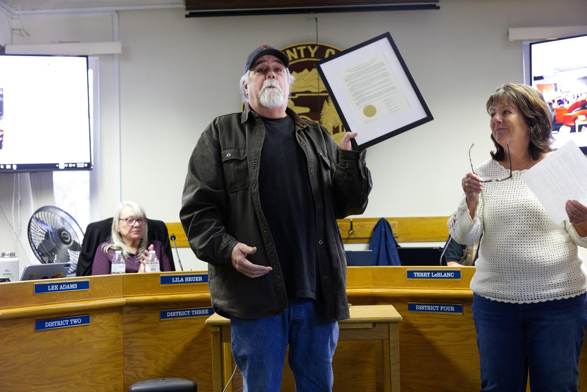 Edward “Ned” Cusato holds up his resolution of appreciation after a presentation by Supervisor Dryden.