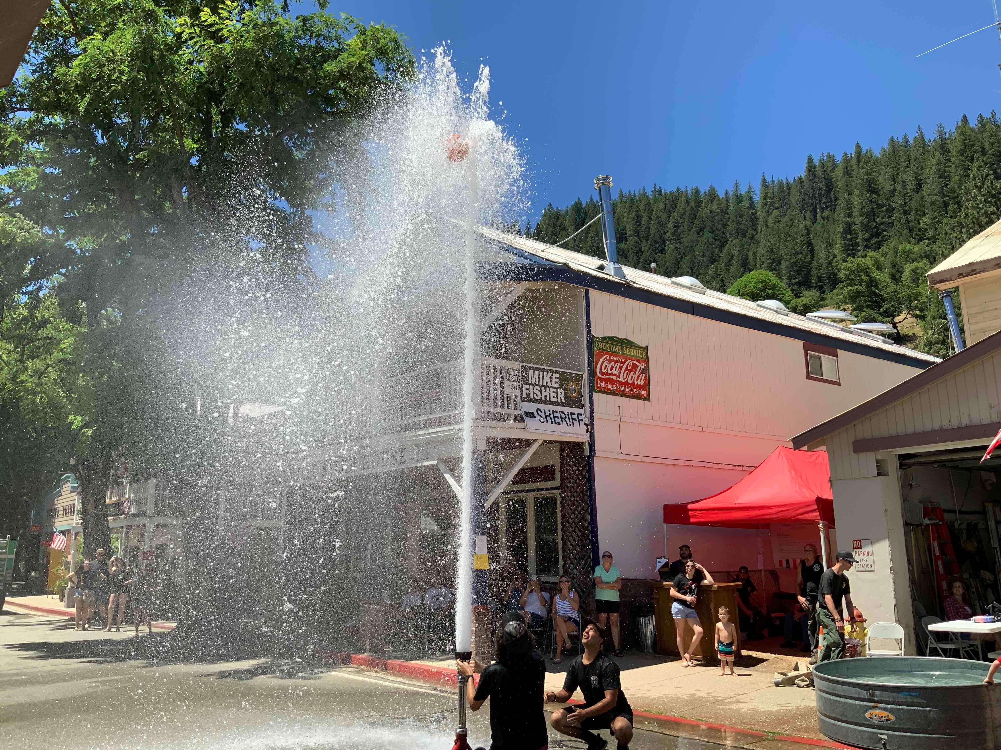 Firefighters raise a basketball with water in the 2022 fireman’s muster.