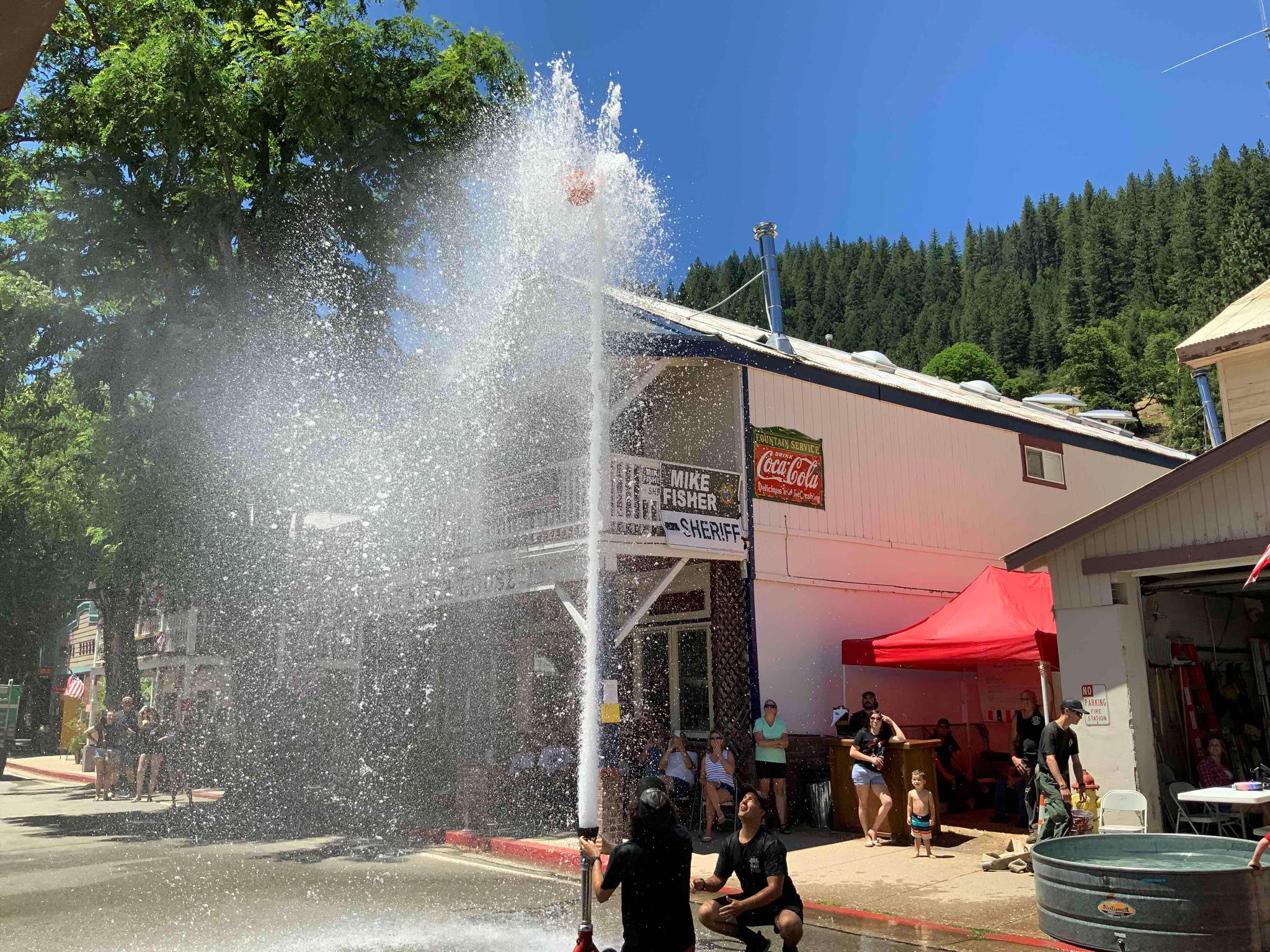 Firefighters raise a basketball with water in the 2022 fireman’s muster.
