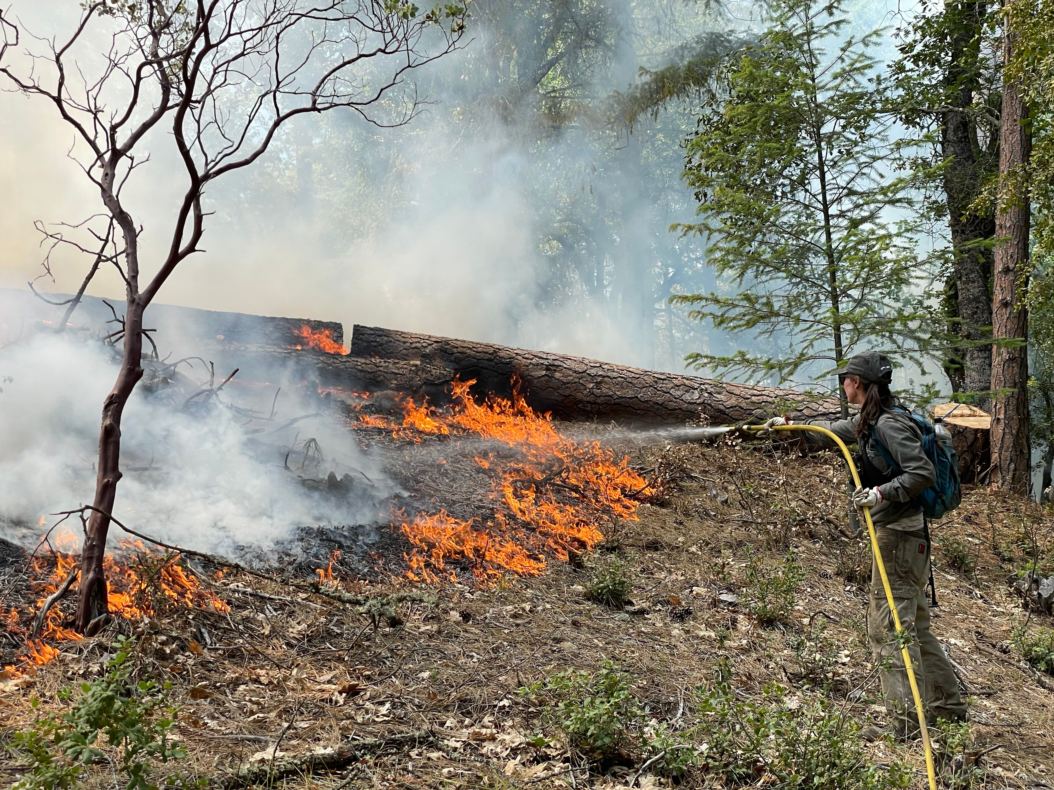 As a training fire grows, Craig demonstrates effective use of a water hose for fire control