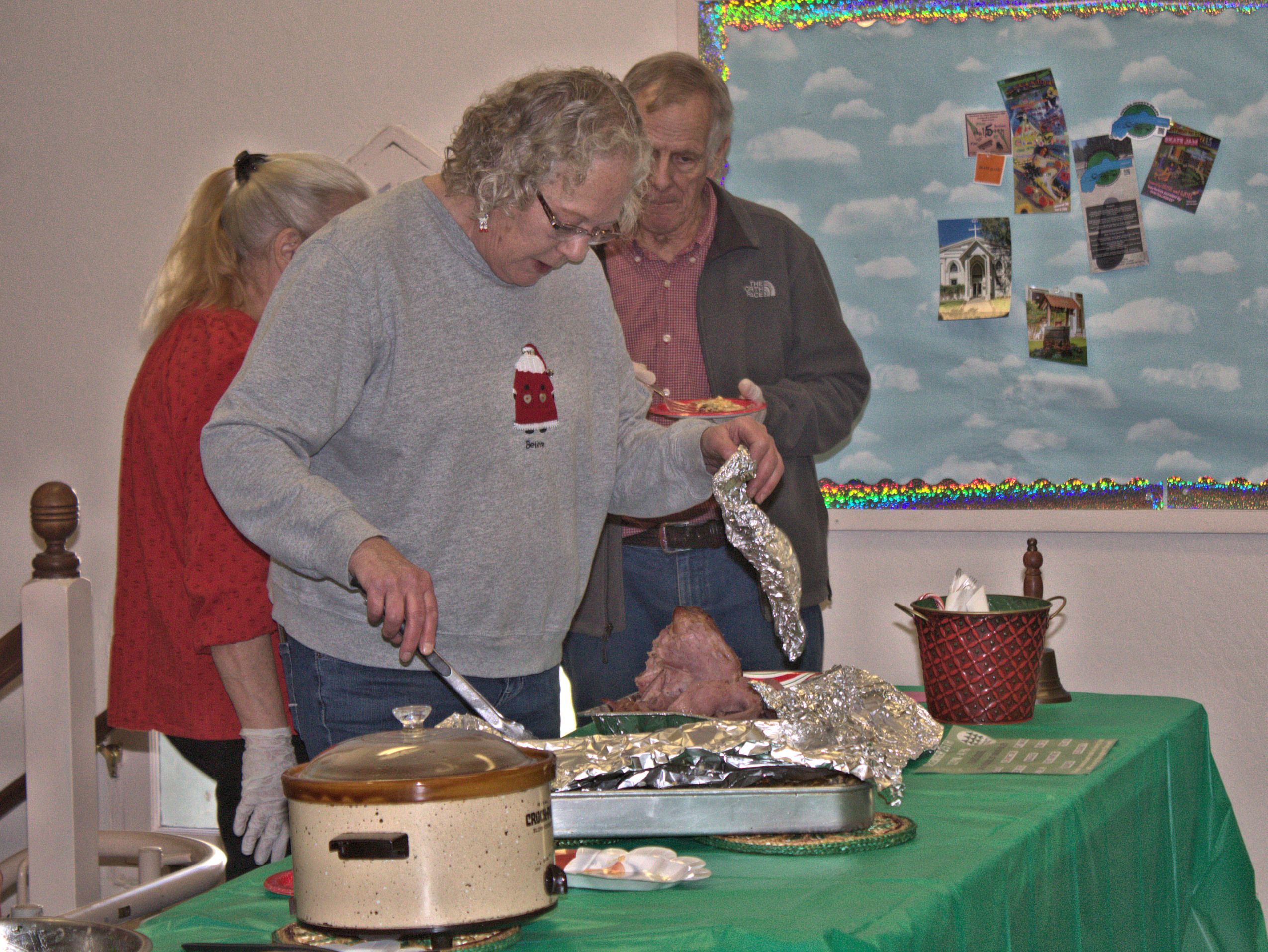 Dianne dishes up scalloped potatoes to go with ham, salad and brownies at the Christmas-week lunch. A choice of soda or (ample) coffee rounded out the festive meal. Photo by Tom Durkin.