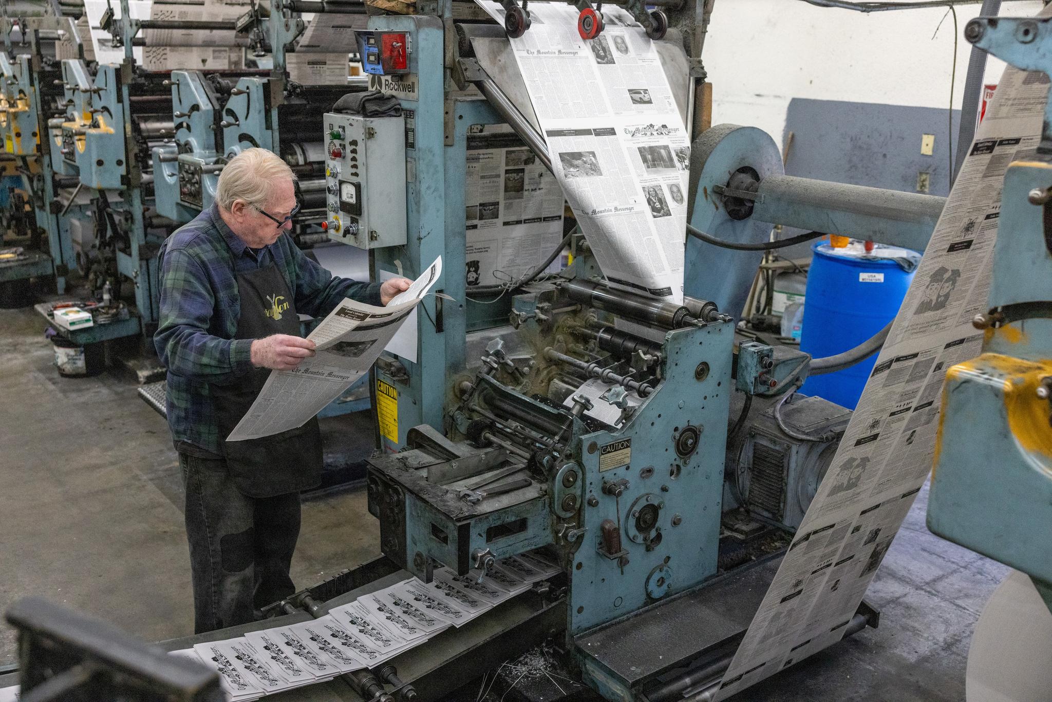 Tom Forney examines the May 30th edition of The Mountain Messenger for defects as it comes off the press