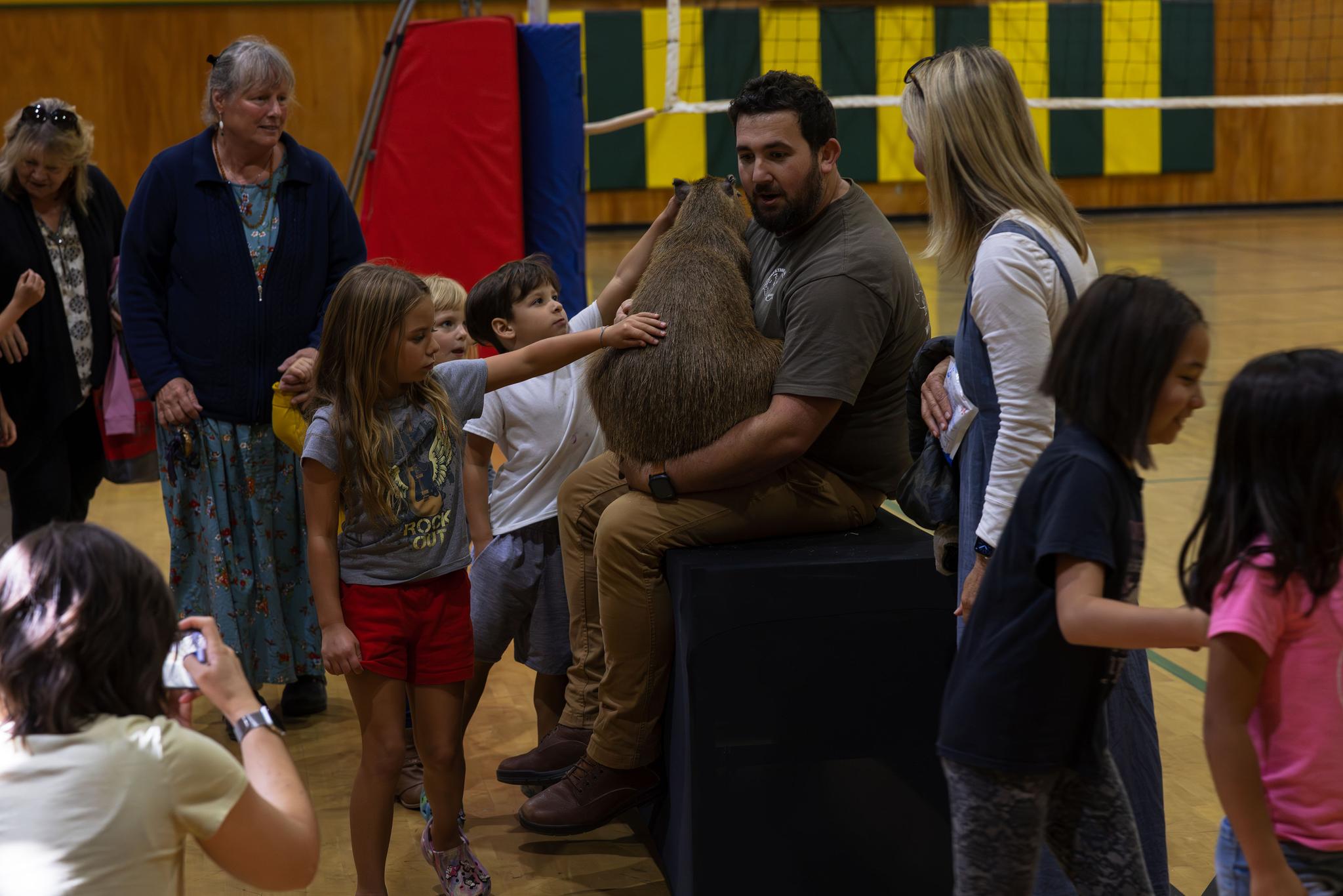 A student pets Tater Tot at the end of the Wild Things assembly.