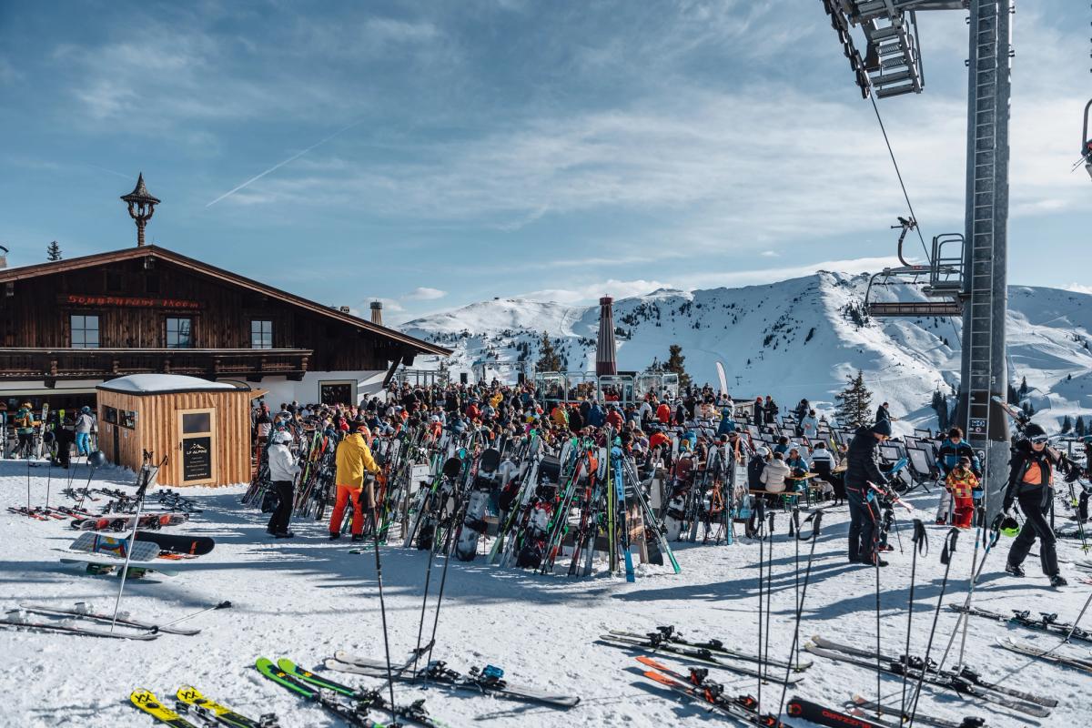 Außenterrasse der Sonnenrast-Schirmbar mit Holztischen und Bänken.