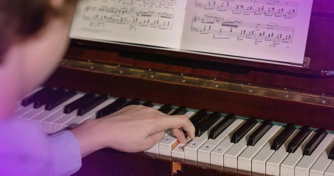 A boy who is playing chord progressions on piano