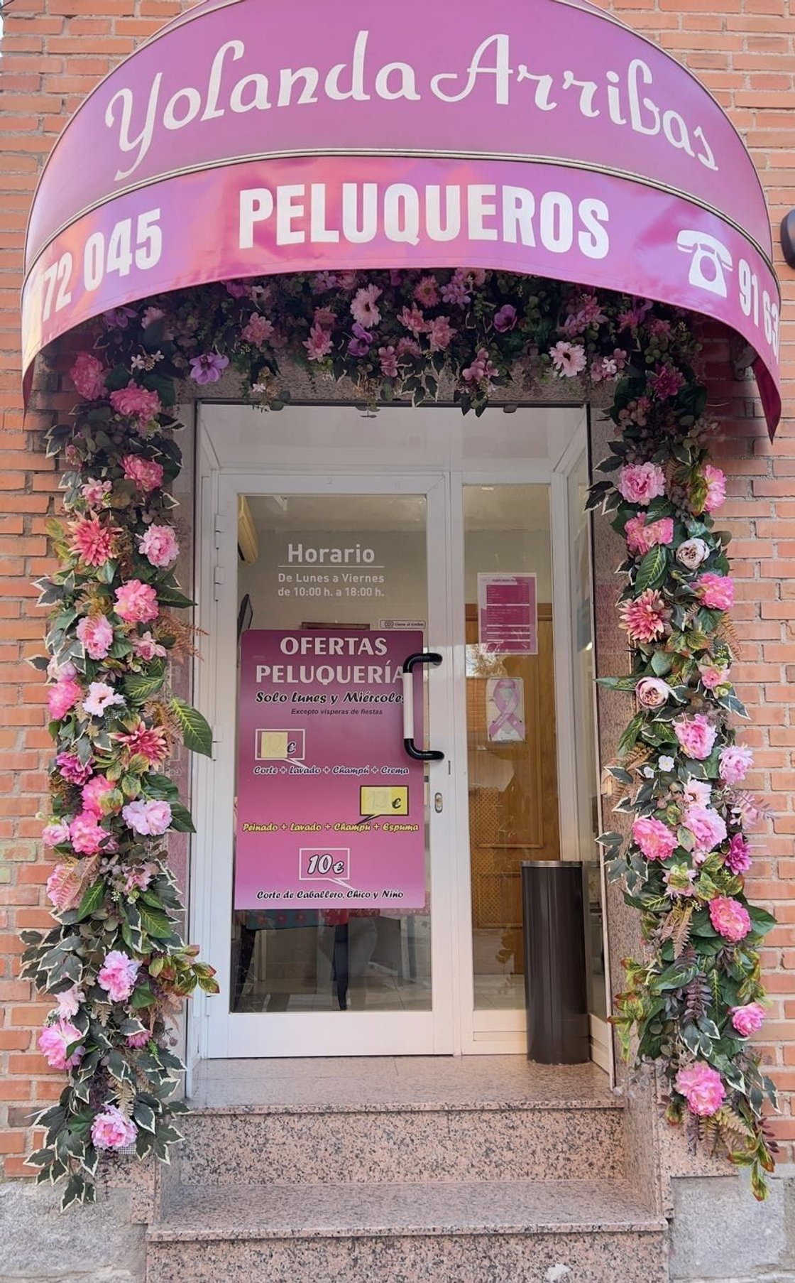 Entrada de Yolanda Arribas Peluqueros, con su toldo rosa y flores