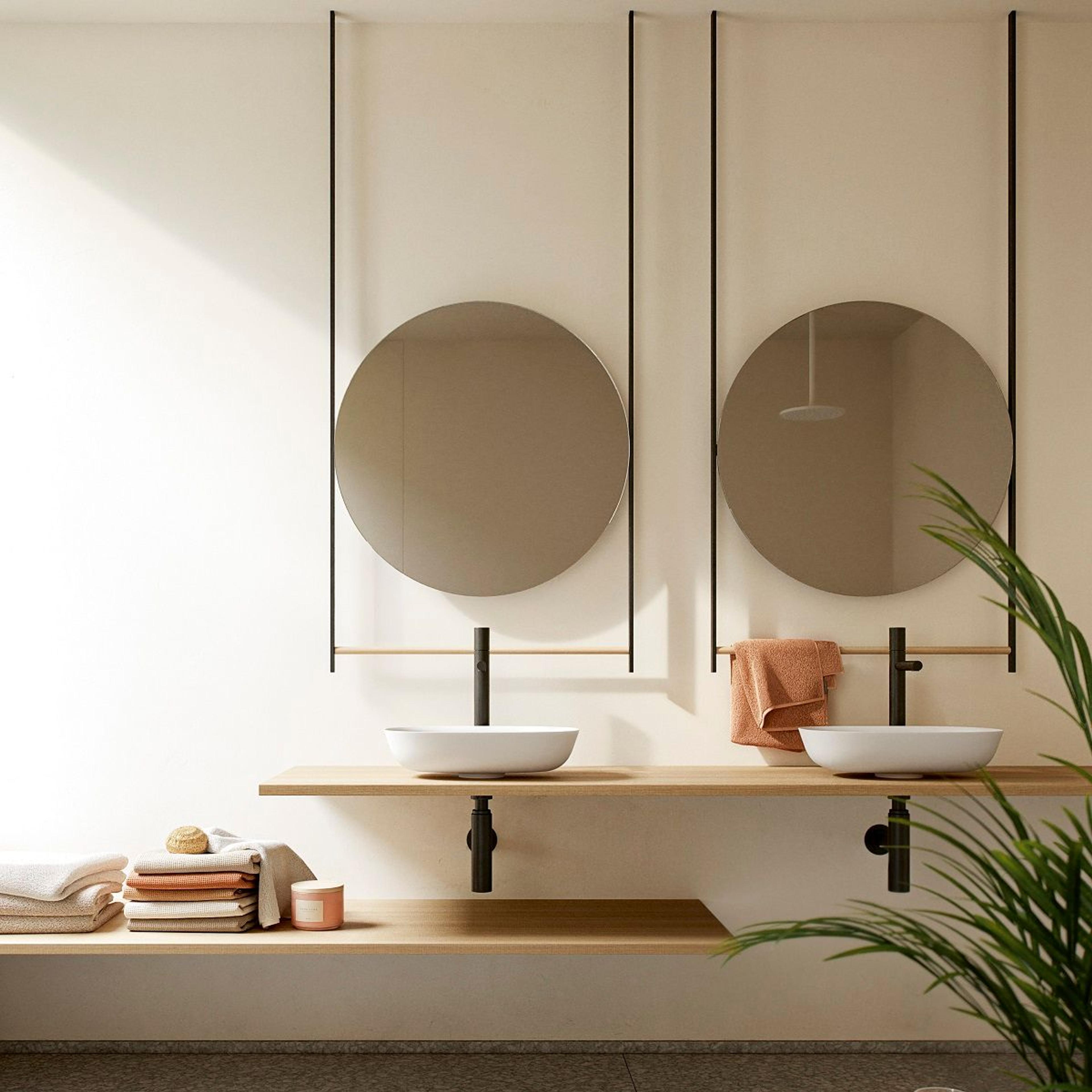 To hvite Solid Surface-servanter med sorte kraner og runde speil.