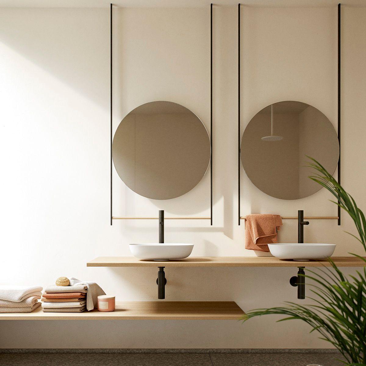 To hvite Solid Surface-servanter med sorte kraner og runde speil.