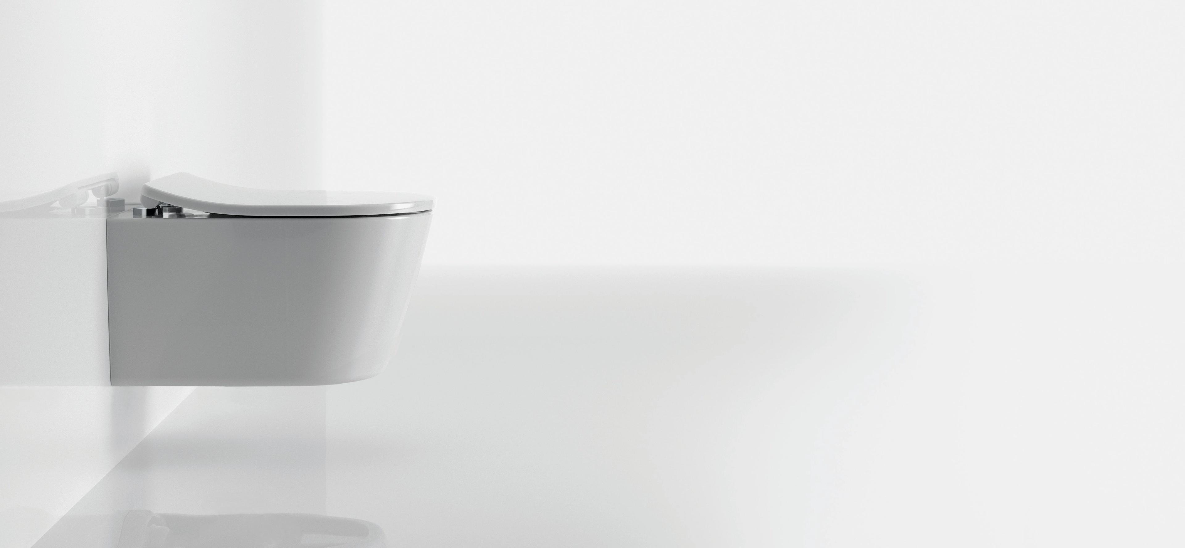 Hvitt vegghengt toalett i et lyst, minimalistisk baderom.
