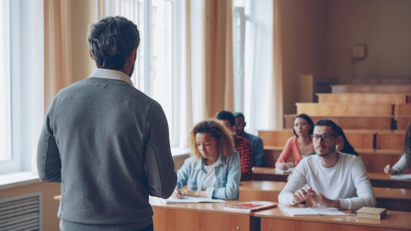 An instructor standing before a class of adult learners seated at desks