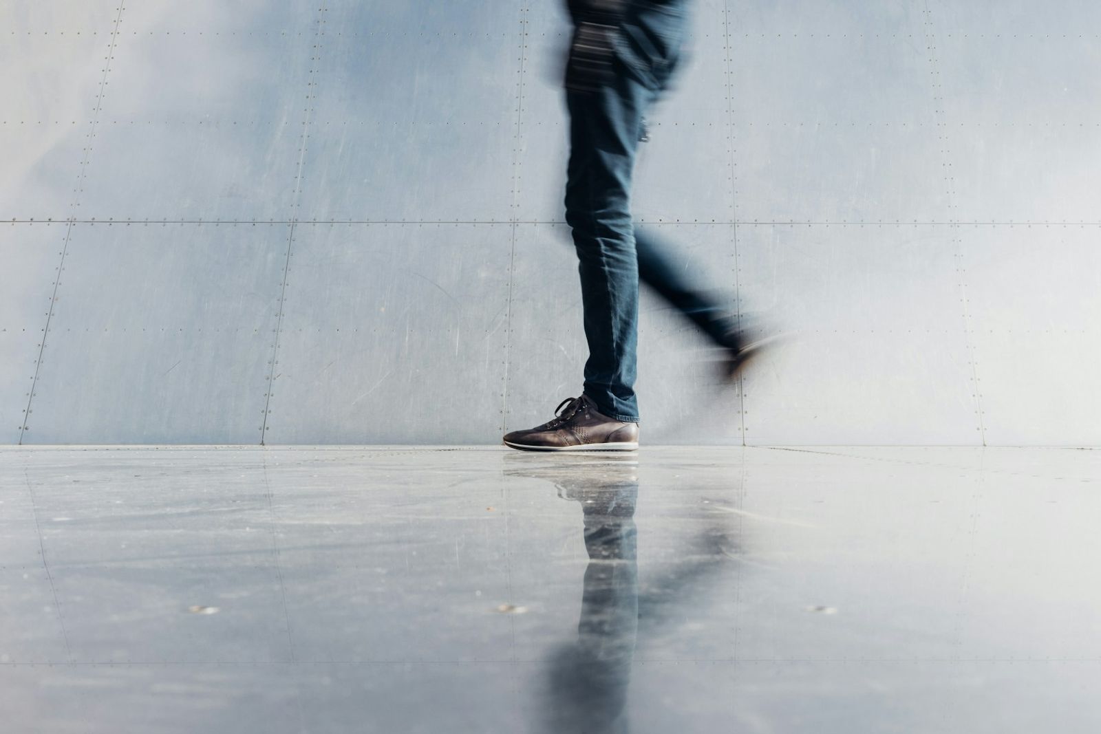 A single figure standing beside a plain concrete wall