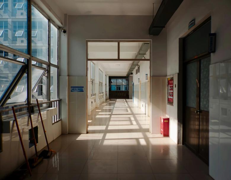 A long, empty hallway with sunlight falling through windows and casting shadows across the floor.