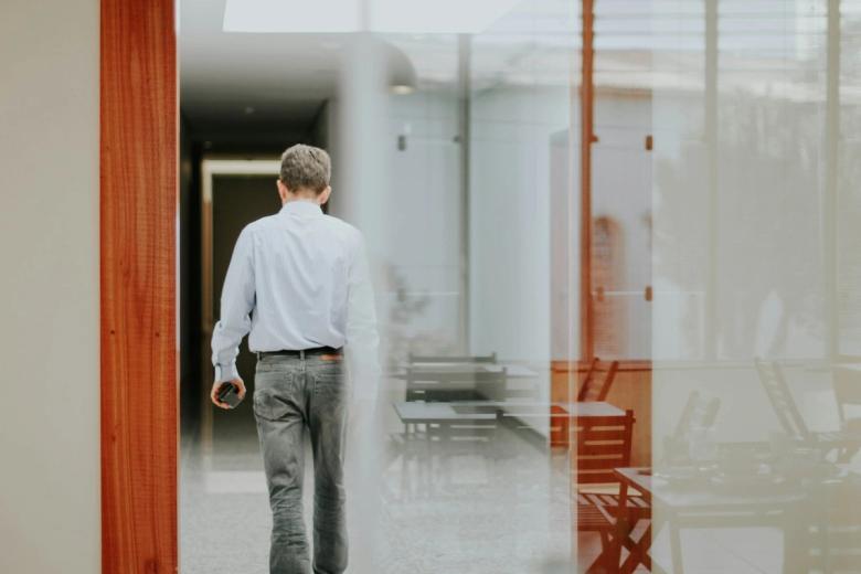 A person walking away down an interior corridor, seen from behind