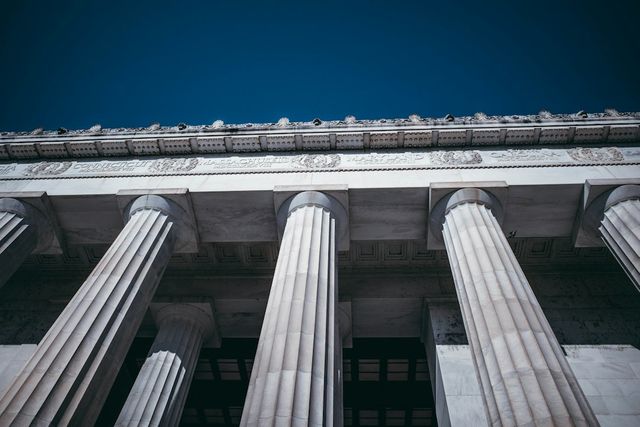 A neoclassical building facade with tall stone columns under a blue sky.