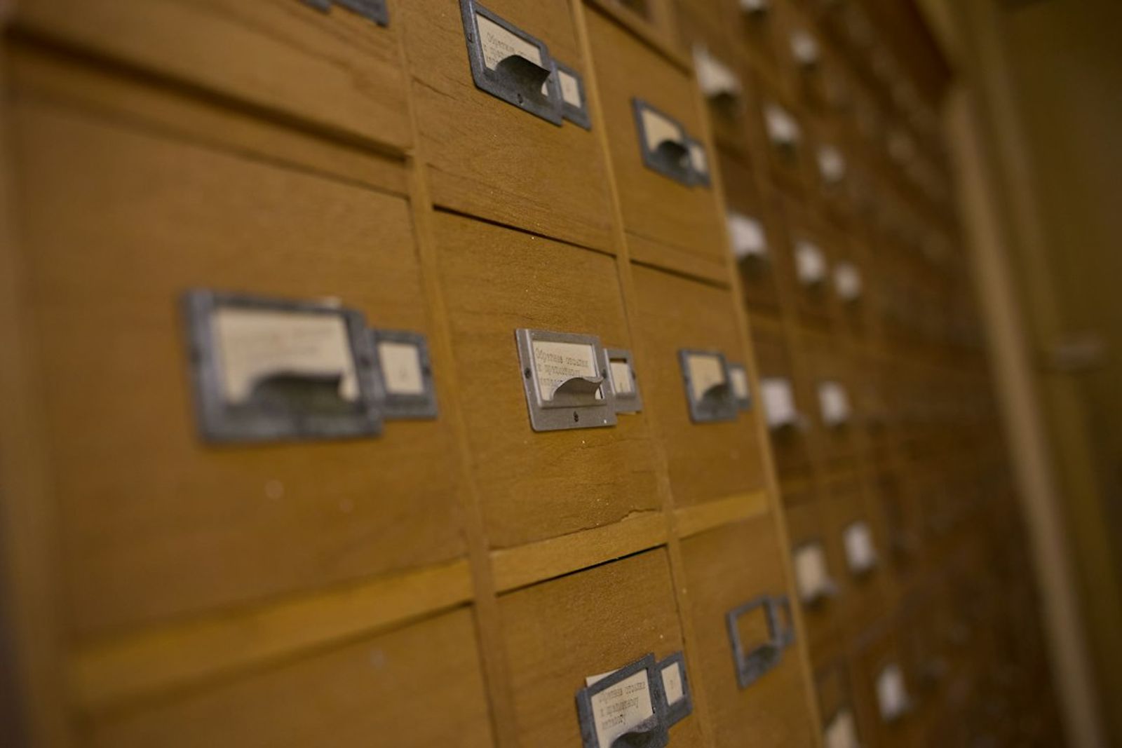 Rows of wooden card catalog drawers with small metal label holders.