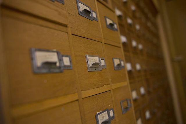 Rows of wooden card catalog drawers with small metal label holders.