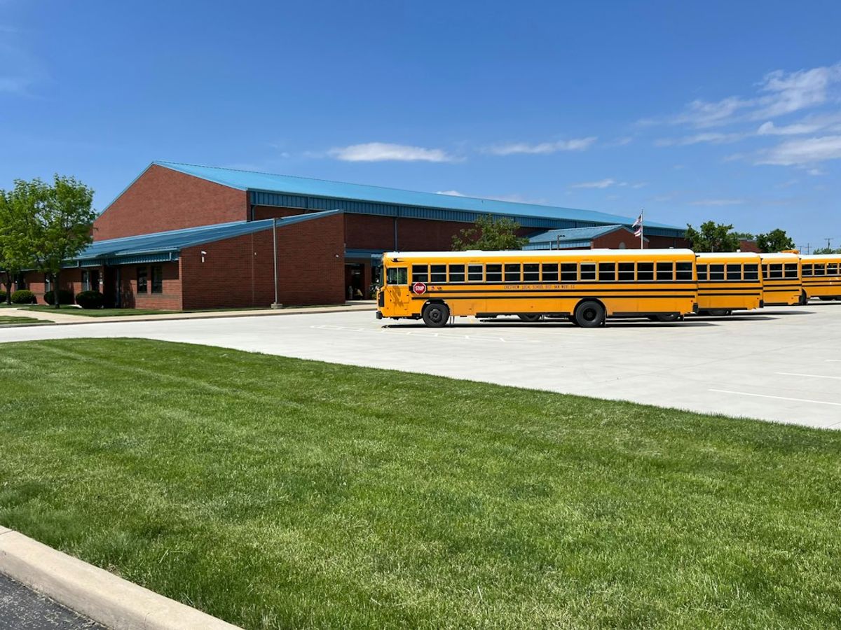 A yellow school bus parked in front of a school building.