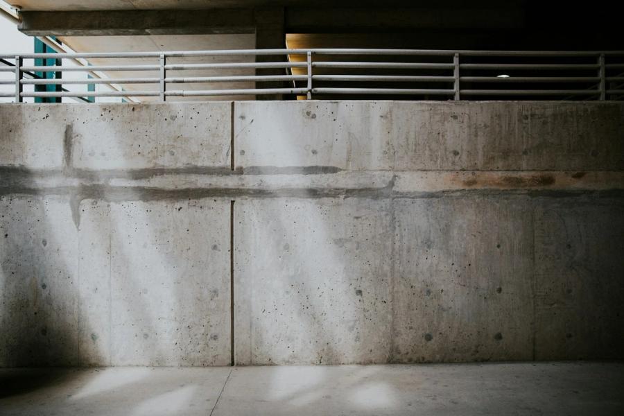 Raking light and railing shadows across a concrete wall