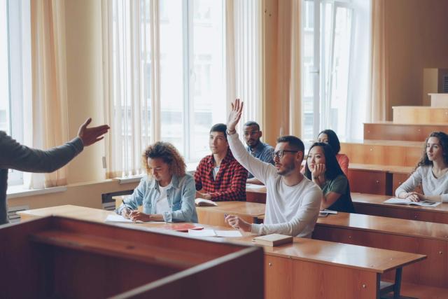 Students raising their hands in a lecture hall