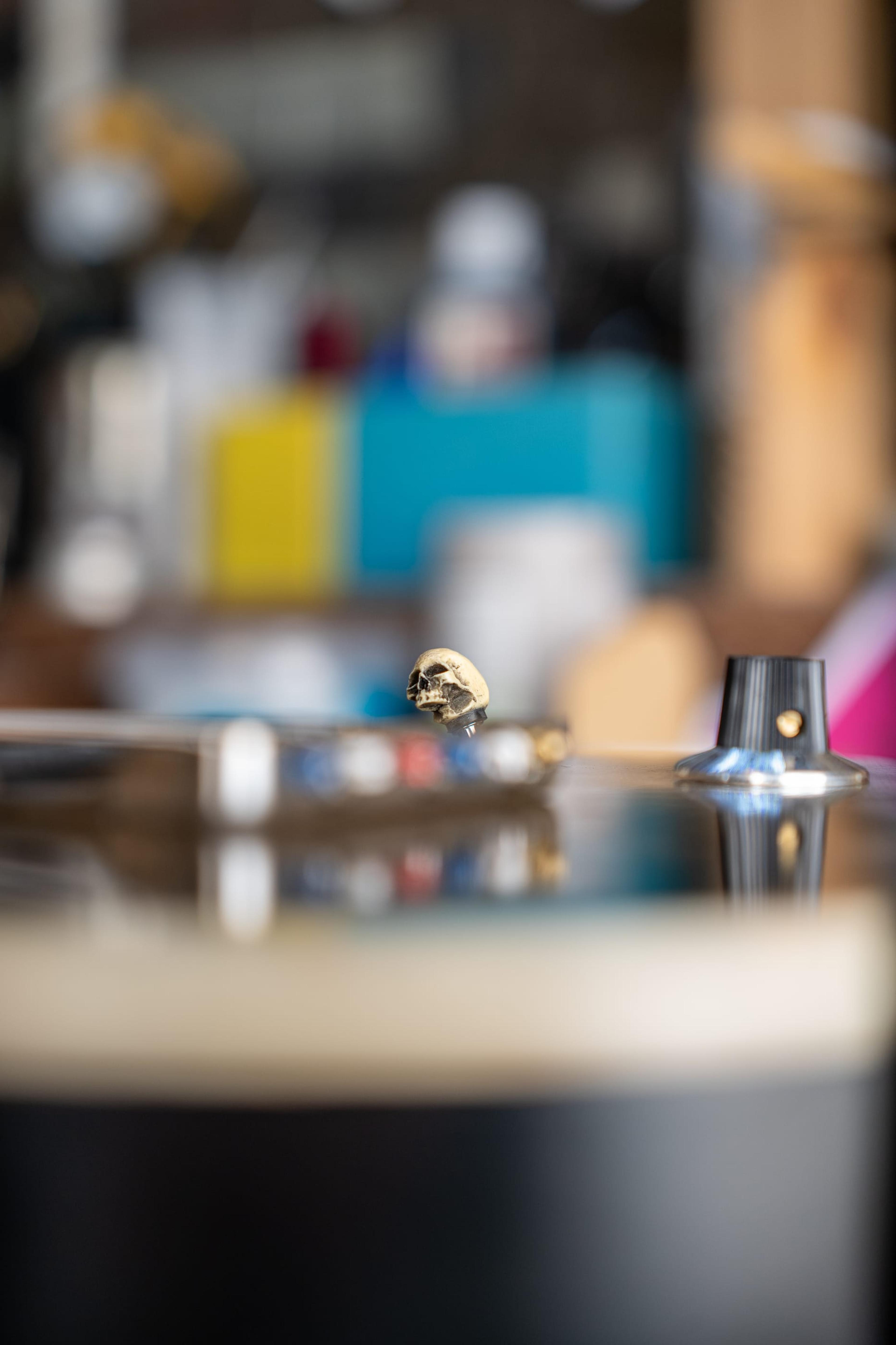 A small skull on the selector switch of a guitar, the shed soft behind it