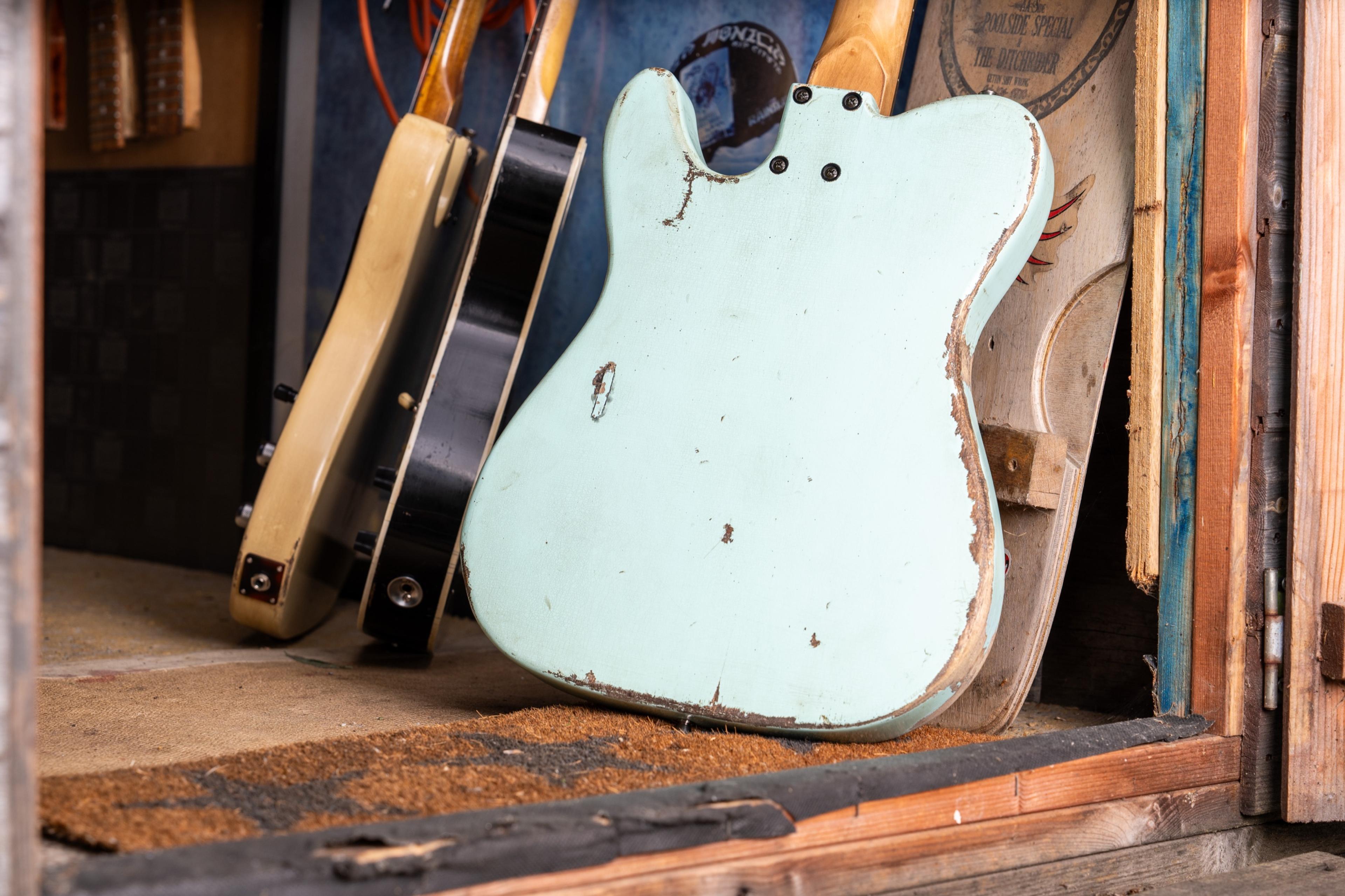 The back of the sonic blue Telecaster, worn through to the wood, leaning in the shed