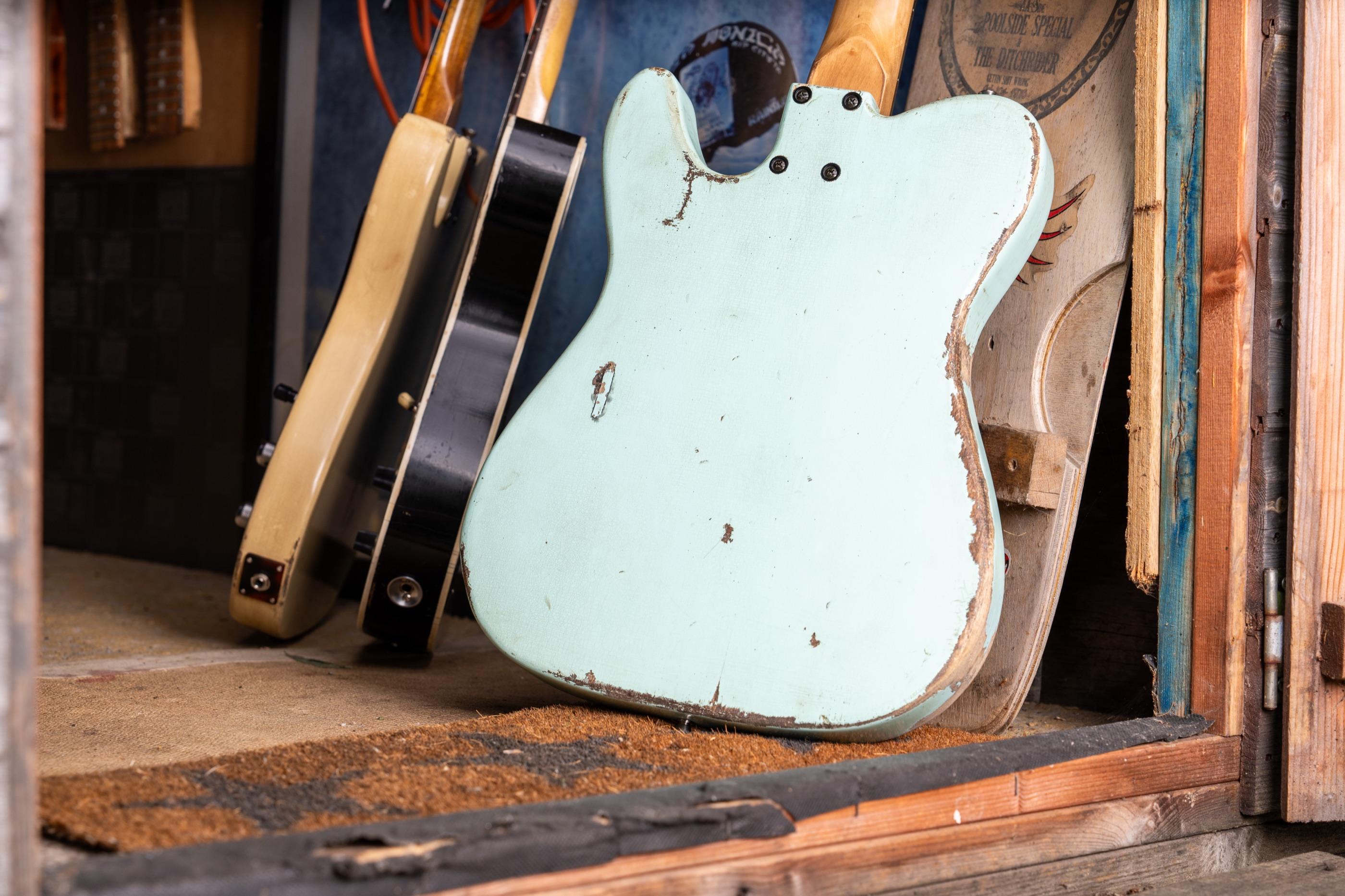 The back of the sonic blue Telecaster, worn through to the wood, leaning in the shed