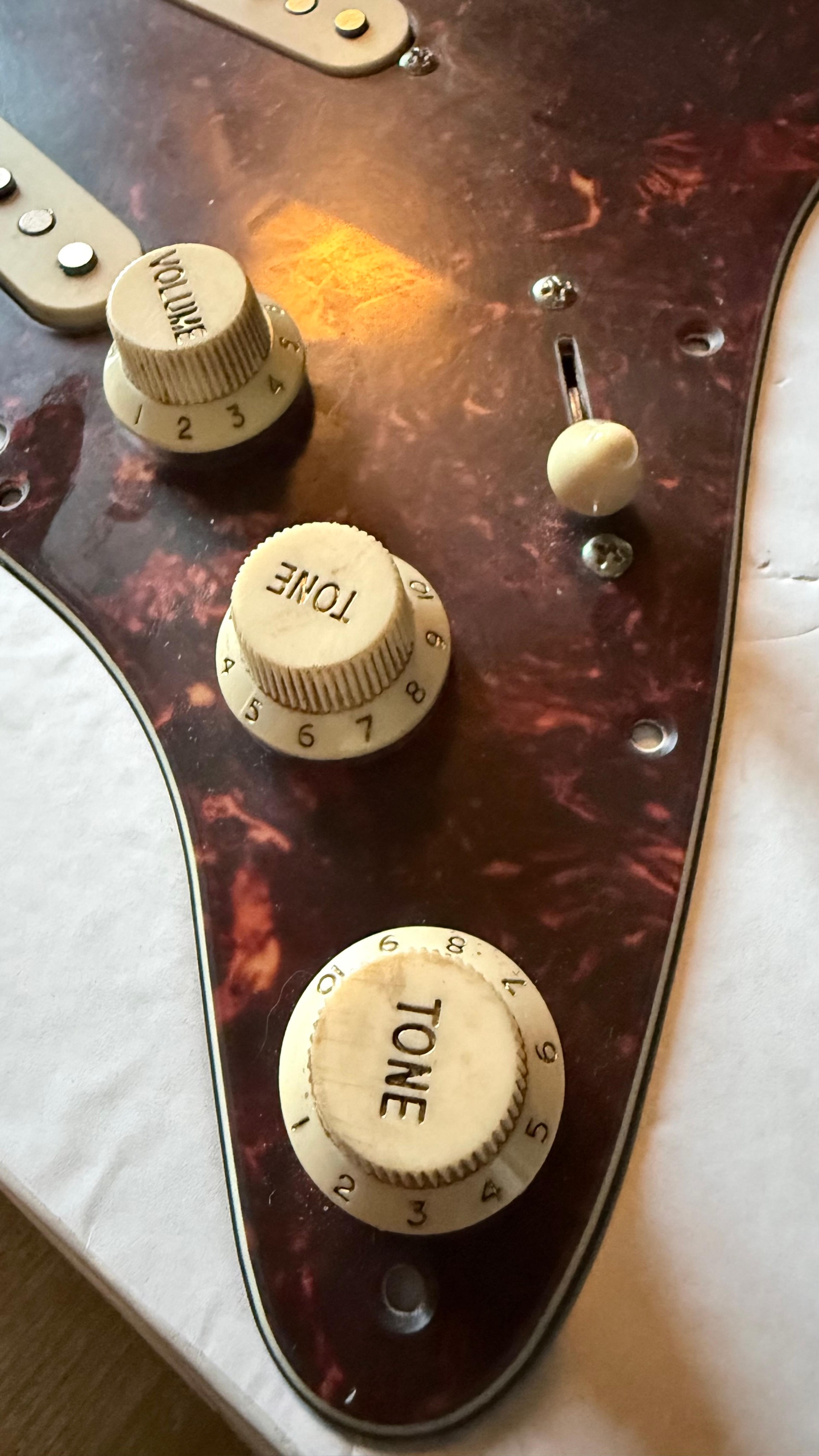 The aged white volume and tone knobs and the switch tip on the tort guard