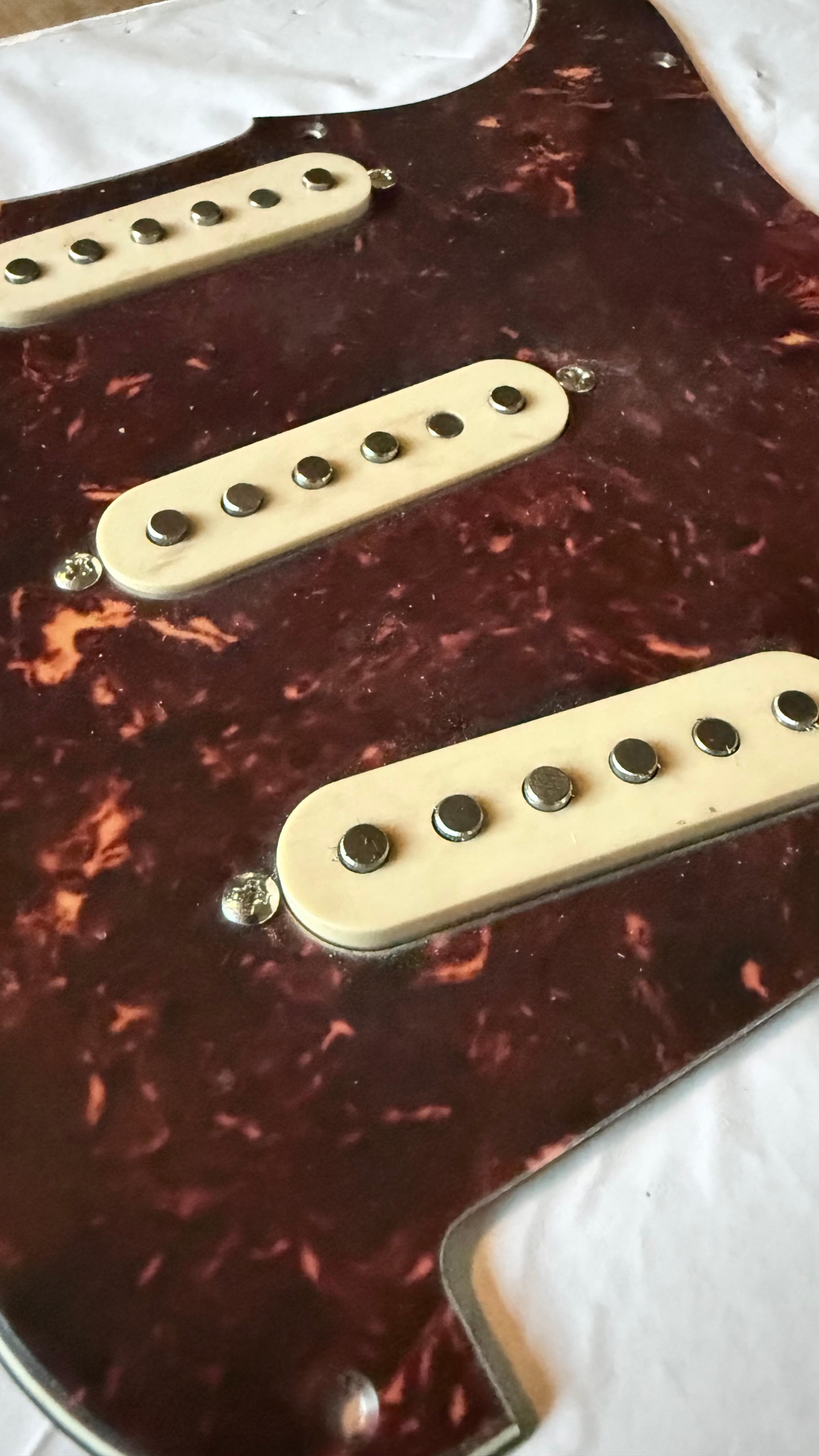 Three single coils under aged white covers on the tort guard