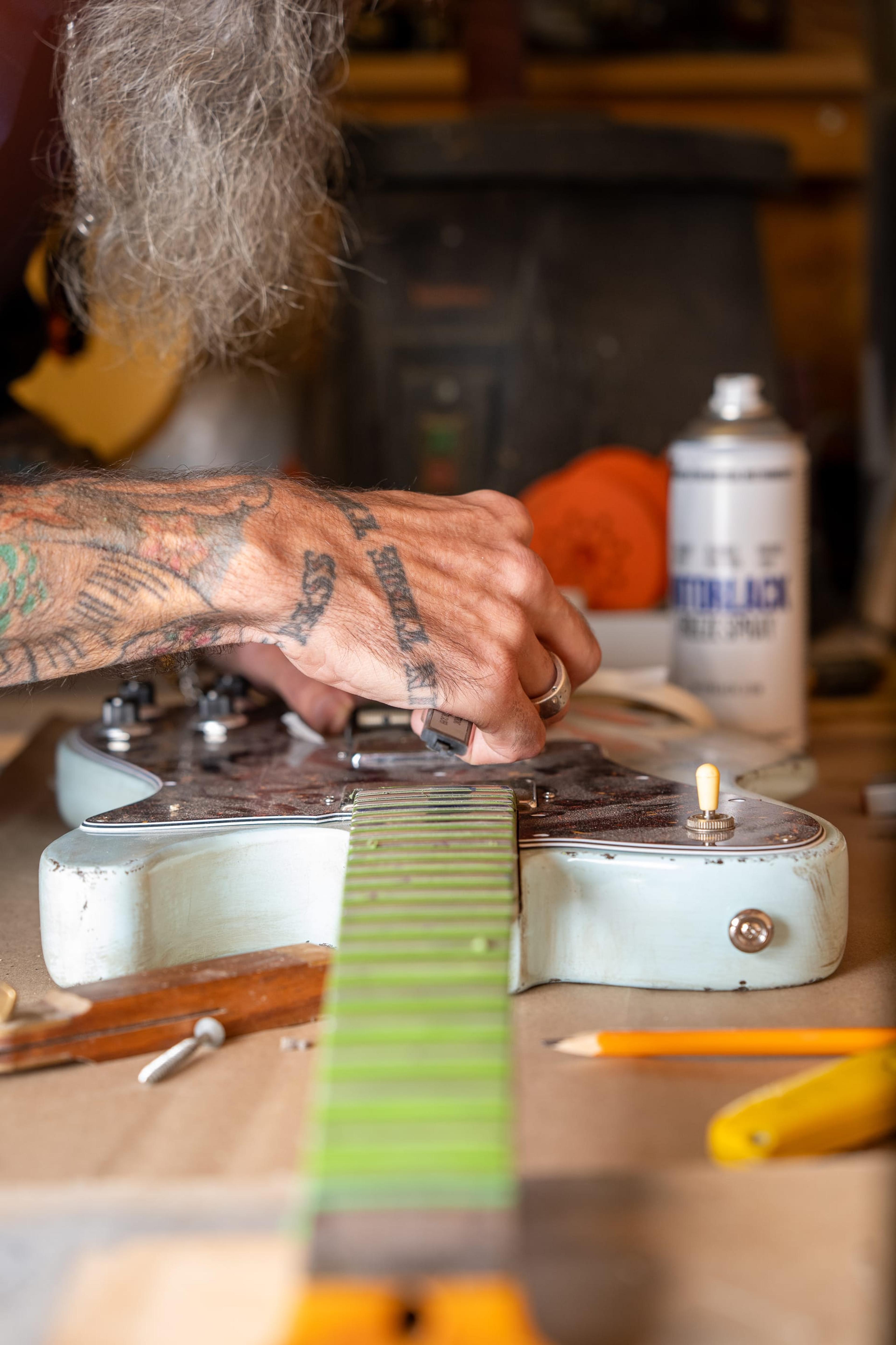 John fitting the pickups and guard to a customer's sonic blue Tele-shaped body on the bench