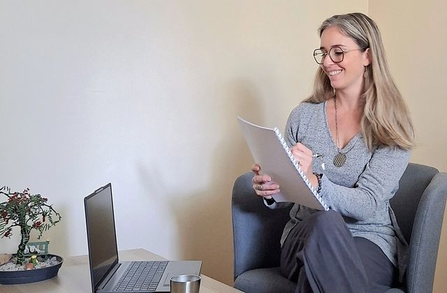 Marine Noiret, naturopathe, prenant des notes pendant un bilan de naturopathie dans son cabinet à Saint-Marcellin