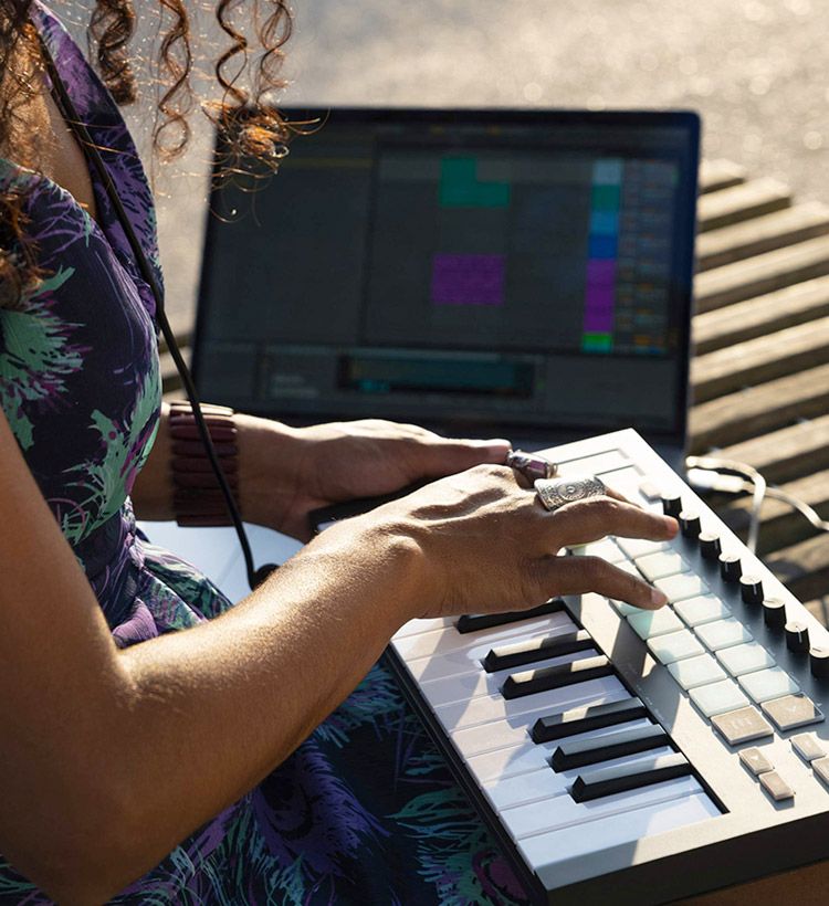 Young woman creating music on a small MIDI keyboard