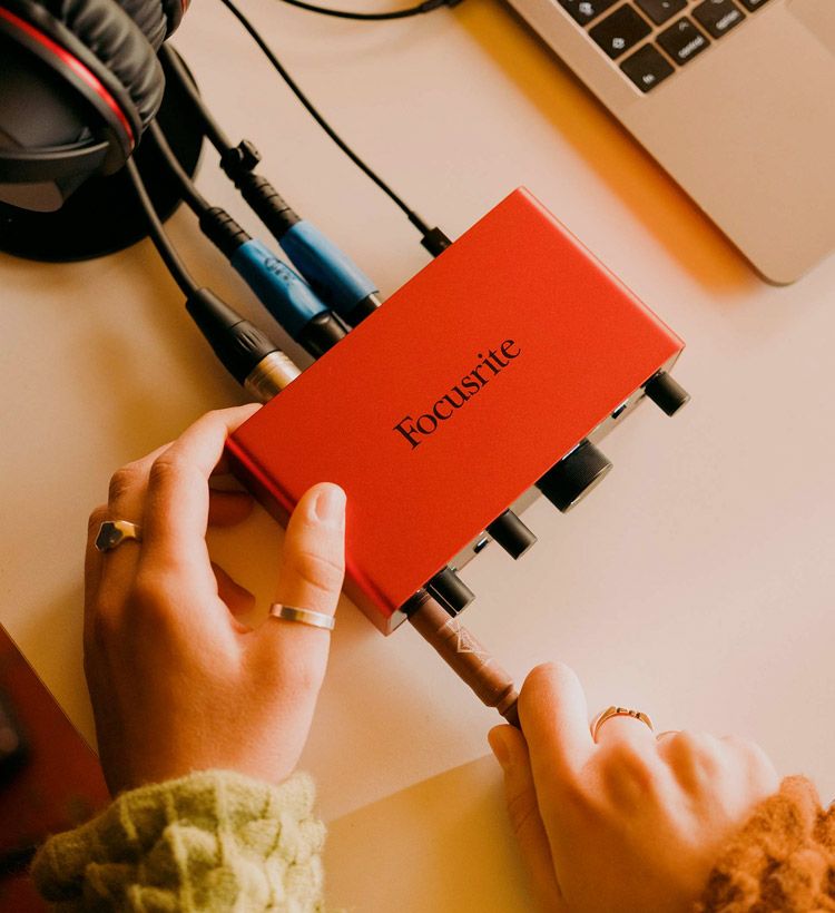 Person plugging in a guitar to a Focusrite audio interface.