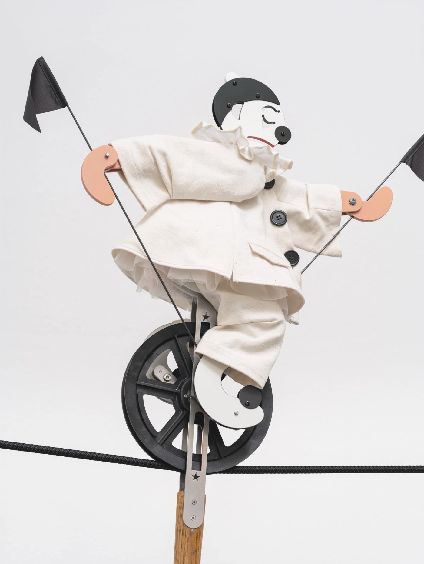 Image of Le Clown, 2024: Sailcloth clothes, tulle petticoat, cotton ruff, synthetic flags, plastic buttons, metal and miscellaneous hardware, Tamiya spray paint, plastic pulley, black synthetic rope, steel engineer’s hammer with wood handle, electric rotating wall apparatus