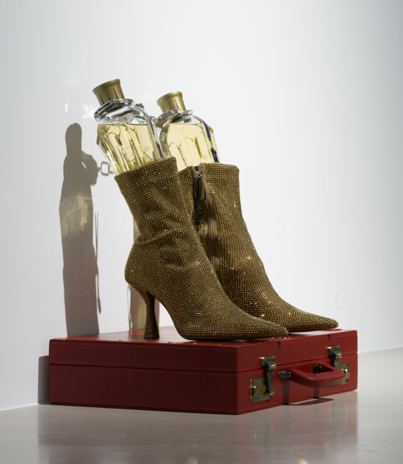 Image of Walk Two Moons, 2023: Mixed media: Crystal boots, two St. Germain
Liqueur bottles, handcuffs, leather briefcase