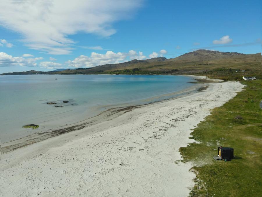 The wood-fired wild sauna parked above the white sand and turquoise water of Corran Sands, Isle of Jura