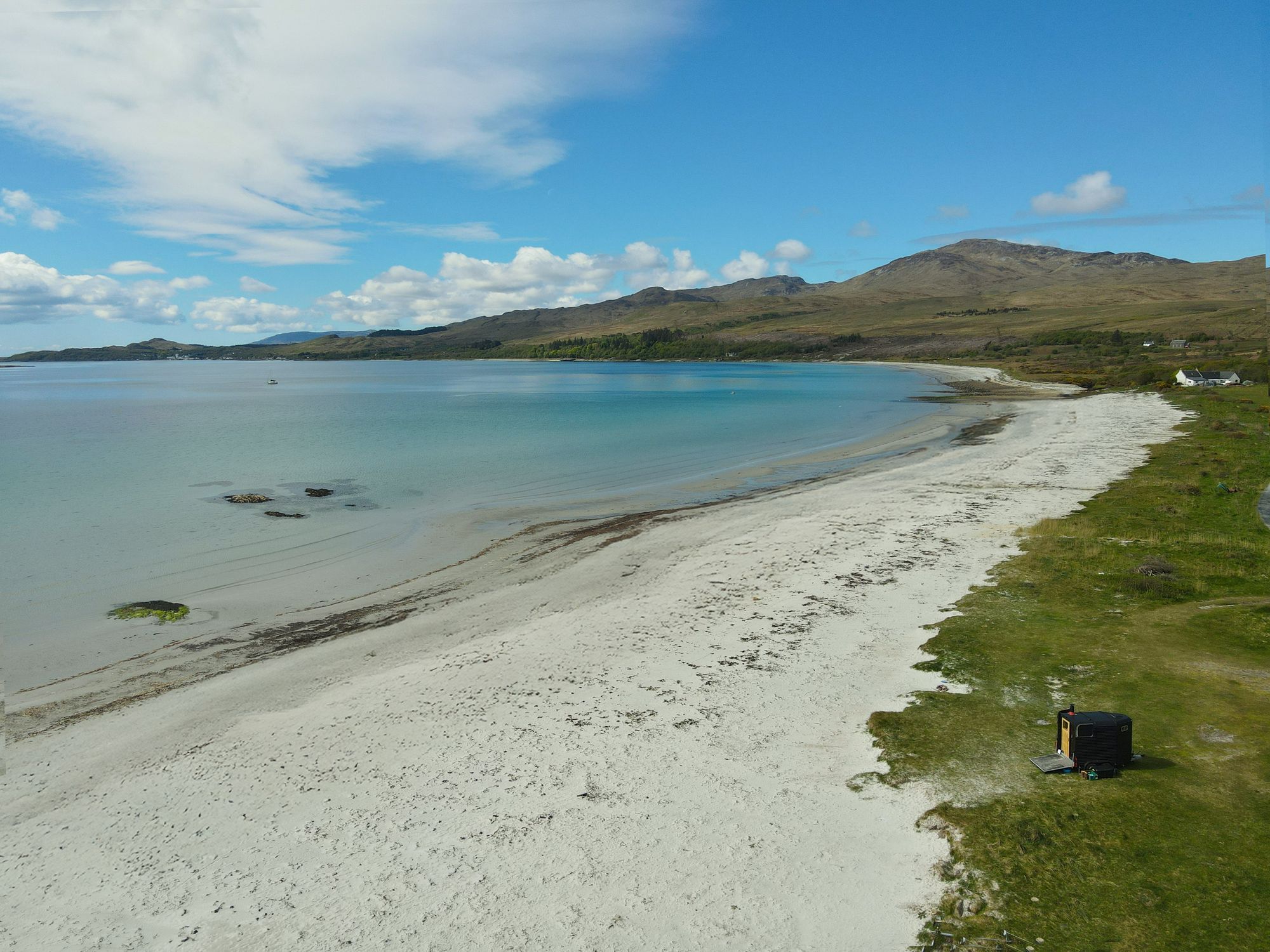 The wood-fired wild sauna parked above the white sand and turquoise water of Corran Sands, Isle of Jura