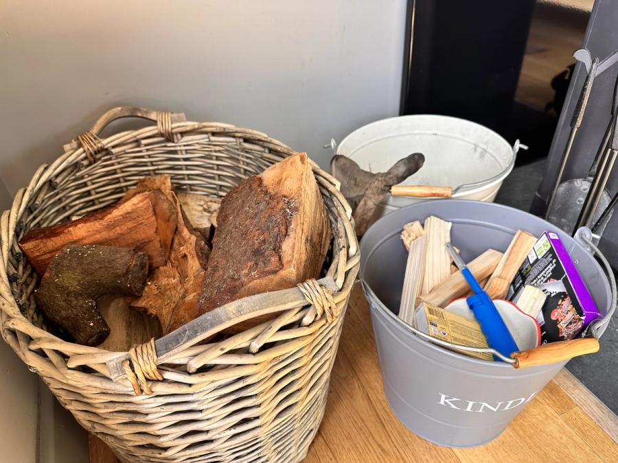 A wicker basket of split logs and a bucket of kindling by the stove at Bothan Jura Retreat, Isle of Jura