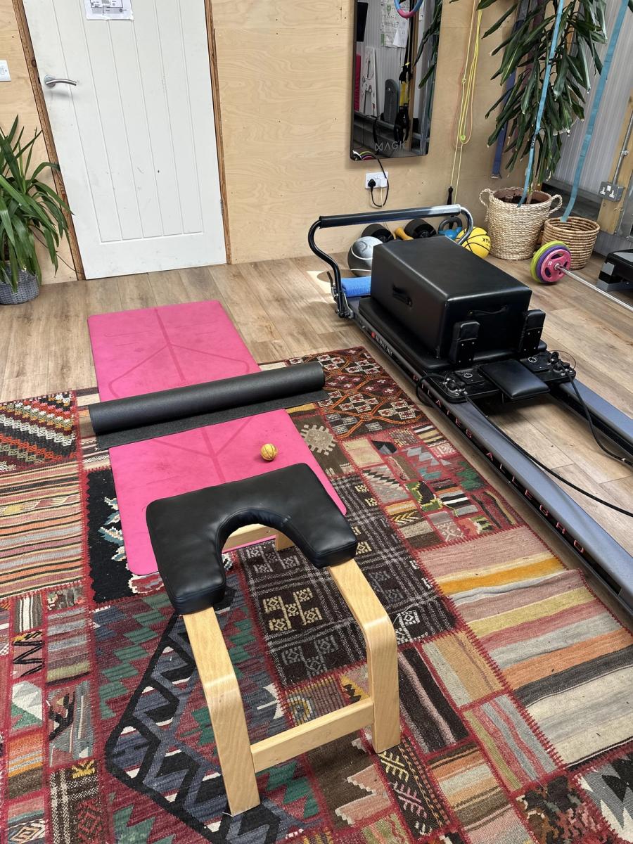 A Pilates reformer and wooden yoga inversion chair with mats in the shed at Bothan Jura Retreat, Isle of Jura
